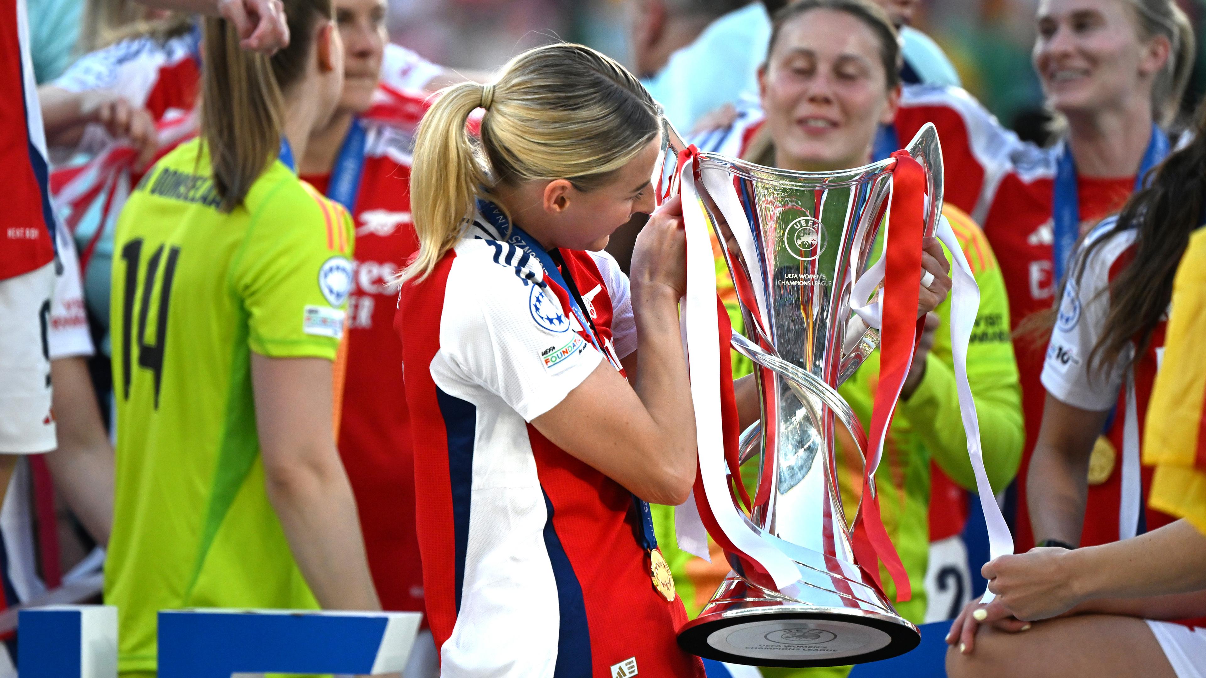 Eine Fußballspielerin des FC Arsenal hält den Champions League Pokal.