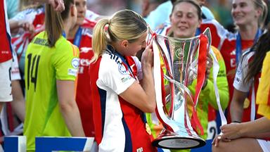 Eine Fußballspielerin des FC Arsenal hält den Champions League Pokal.