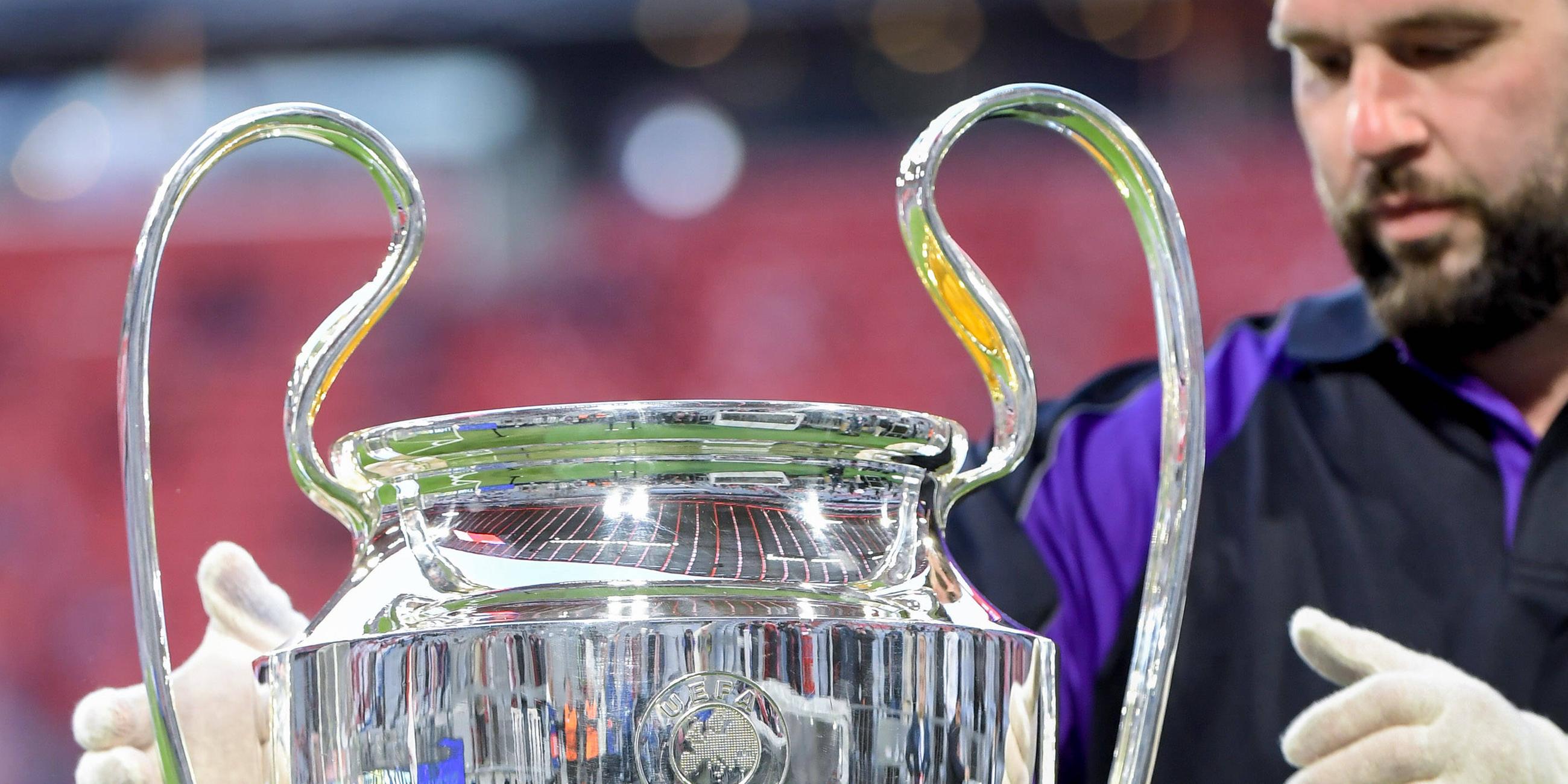 Ein Helfer platziert den Champions-League-Pokal auf einem Podest