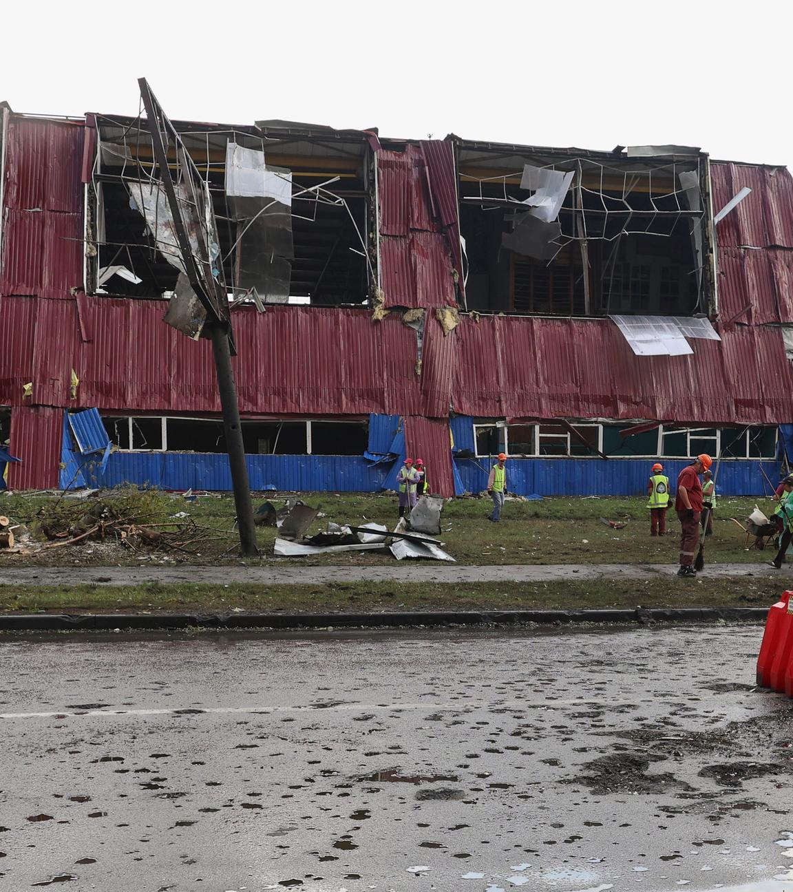 People clean debris at the site of a Russian strike on a sports complex in a residential area in Kharkiv, northern Ukraine, 26 July 2025, amid the ongoing Russian invasion.