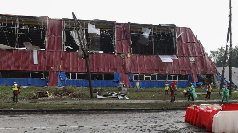 People clean debris at the site of a Russian strike on a sports complex in a residential area in Kharkiv, northern Ukraine, 26 July 2025, amid the ongoing Russian invasion.