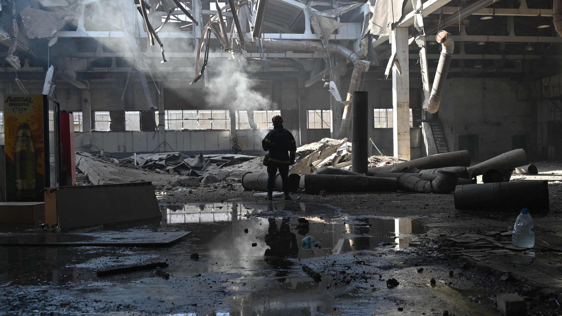Ein ukrainischer Feuerwehrmann arbeitet in der Werkstatt eines privaten Unternehmens nach einem russischen Drohnenangriff in Charkiw am 22. April 2025