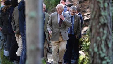 Das Bild zeigt König Charles und weitere Menschen, die durch den Nationalpark laufen.