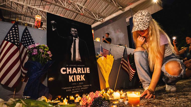 Eine Frau stellt eine Kerze nieder vor einem Gedenkort für Charlie Kirk in Florida.