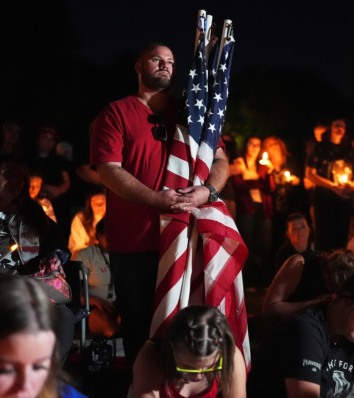 Bei einer Mahnwache in Provo, Utah, hält ein Mann US-amerikanische Flaggen für den getöteten US-Aktivisten Charlie Kirk. 