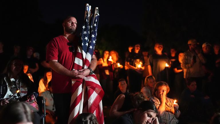 Bei einer Mahnwache in Provo, Utah, hält ein Mann US-amerikanische Flaggen für den getöteten US-Aktivisten Charlie Kirk. 