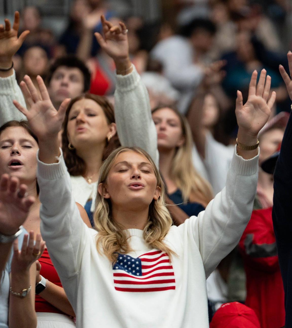 Teilnehmer heben die Hände und singen während einer Gedenkfeier für Charlie Kirk im State Farm Stadium in Glendale am 21. Sept. 2025.