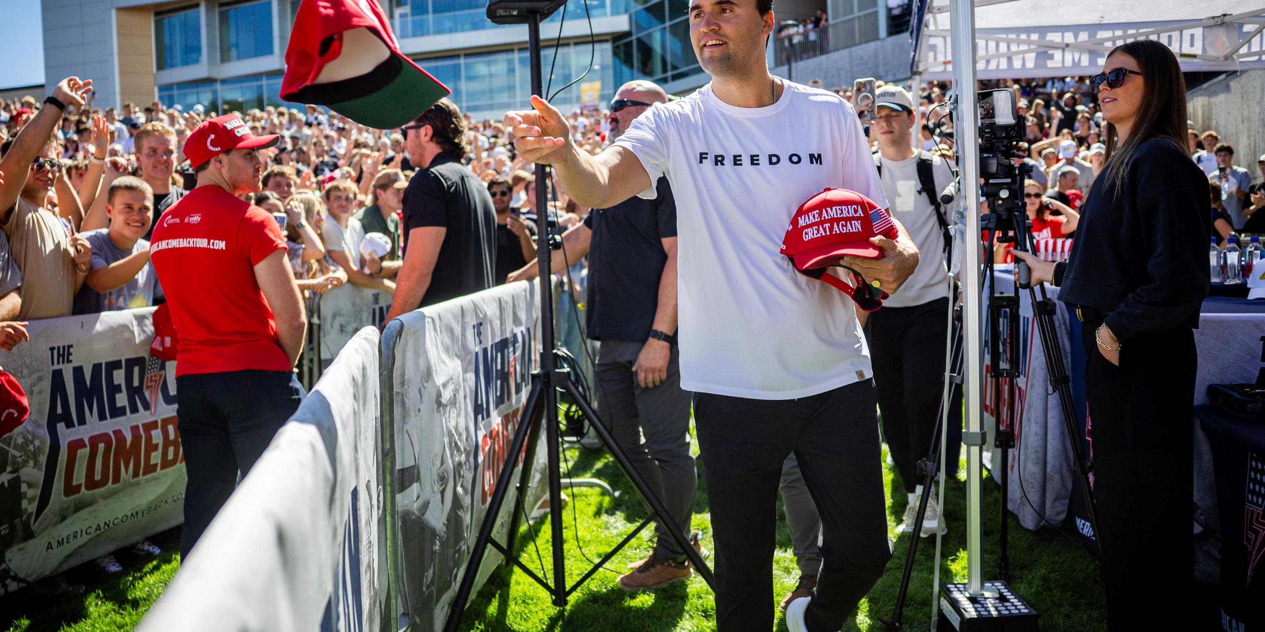 Charlie Kirk verteilt vor seiner Rede an der Utah Valley University Mützen. 