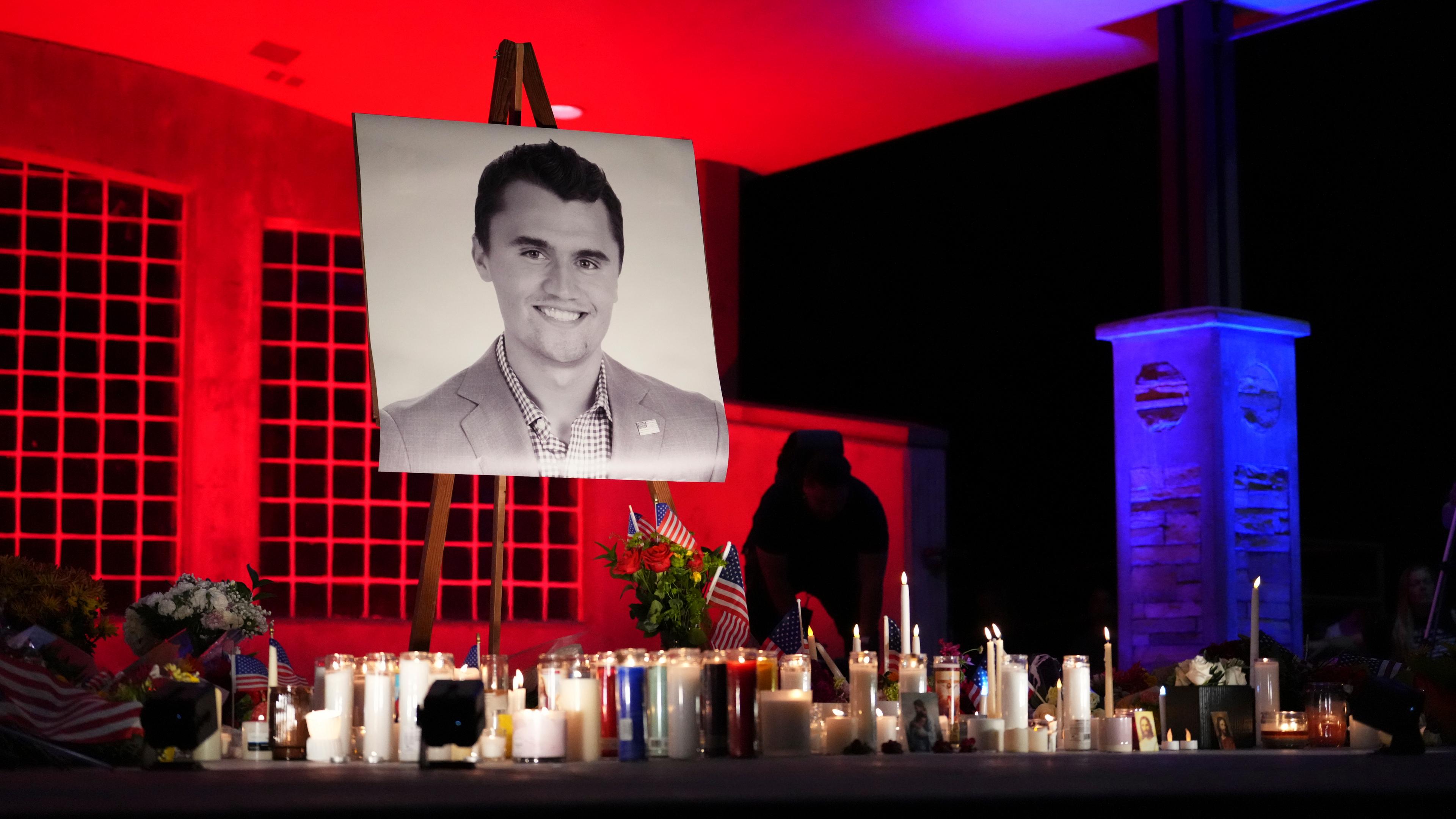 Ein Foto von Charlie Kirk steht auf einer Staffelei, darunter mehrere brennende Kerzen.