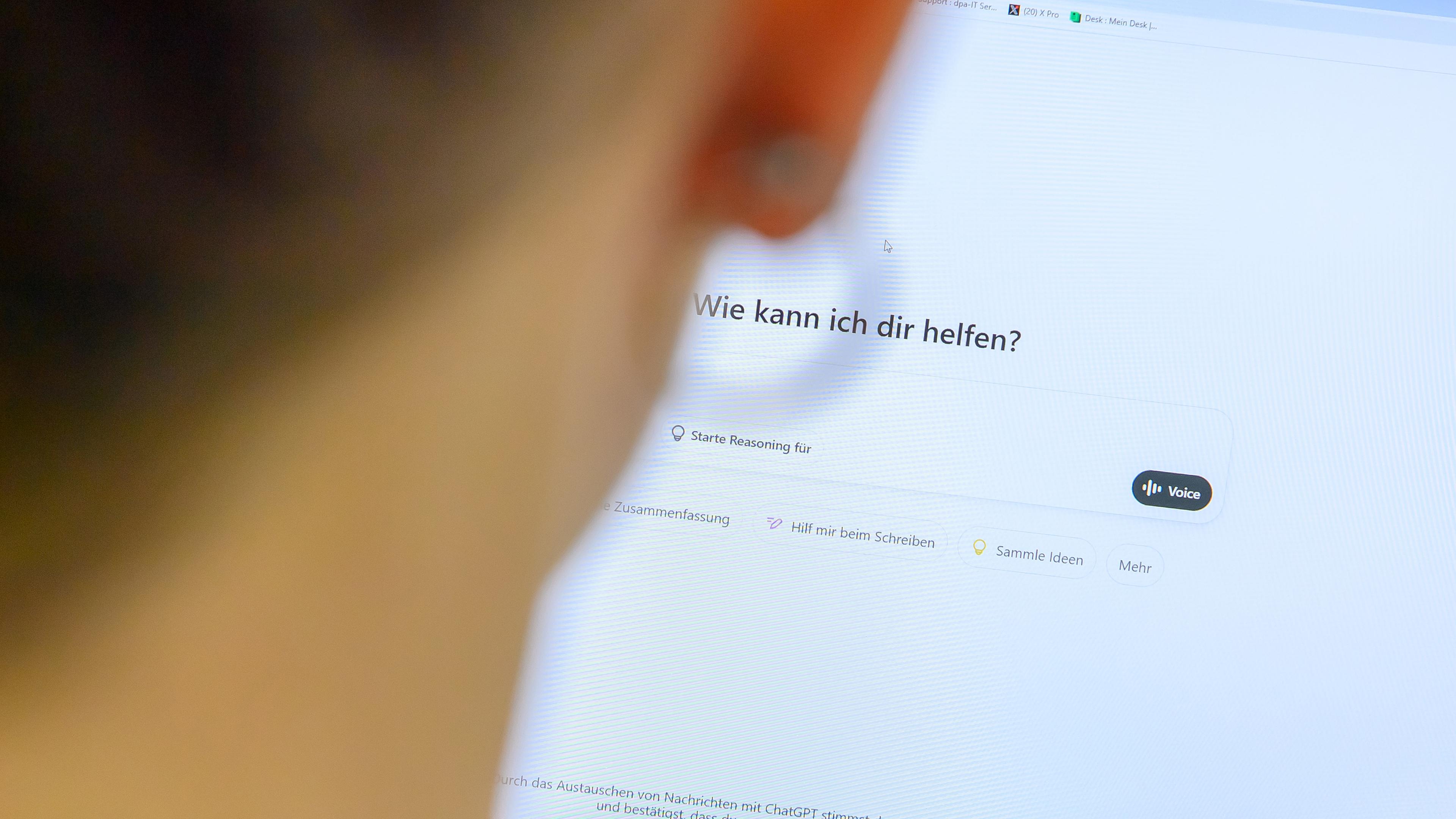 Eine Frau sitzt am Computer und gibt etwas bei "ChatGPT" in die Suchmaske ein.
