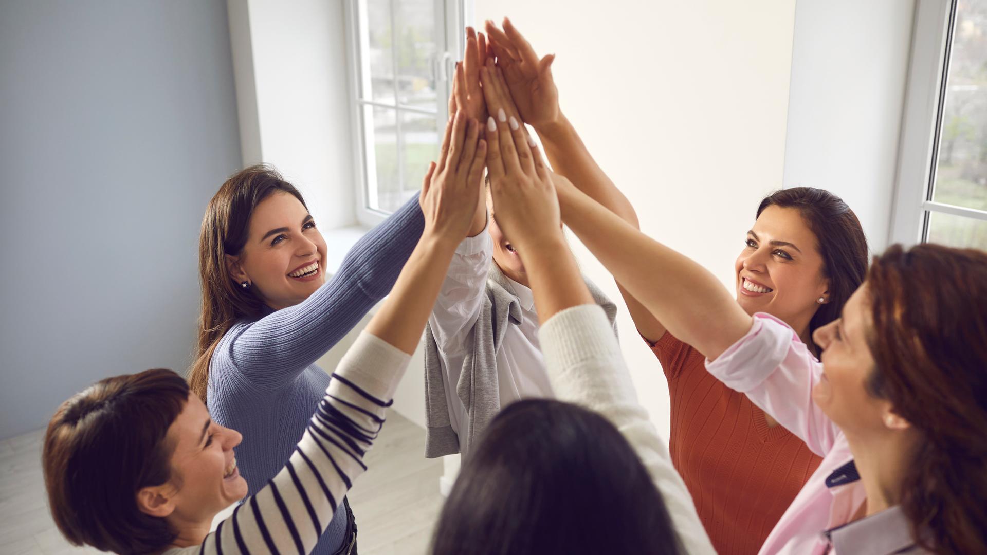 Ein Team steht in einem Kreis und schlägt die Hände in der Mitte zusammen.