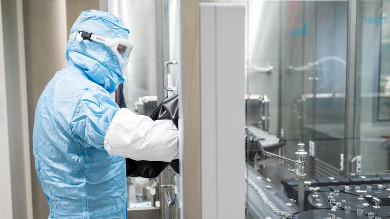 Ein Arbeiter steht an einer Abfüll- und Verschließanlage für pharmazeutische Produkte bei Takeda Pharmaceutical.