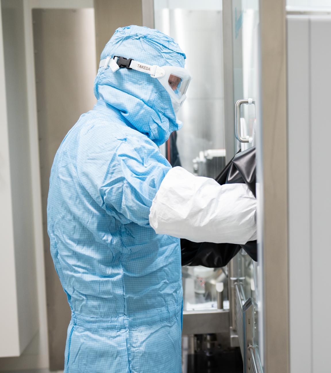 Ein Arbeiter in Schutzkleidung steht an einer Abfüll- und Verschließanlage für pharmazeutische Produkte bei Takeda Pharmaceutical.