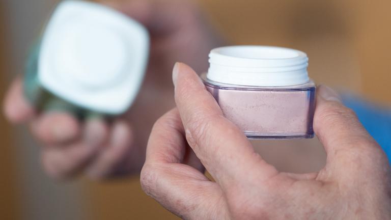 Frau hält Cremedose in der Hand