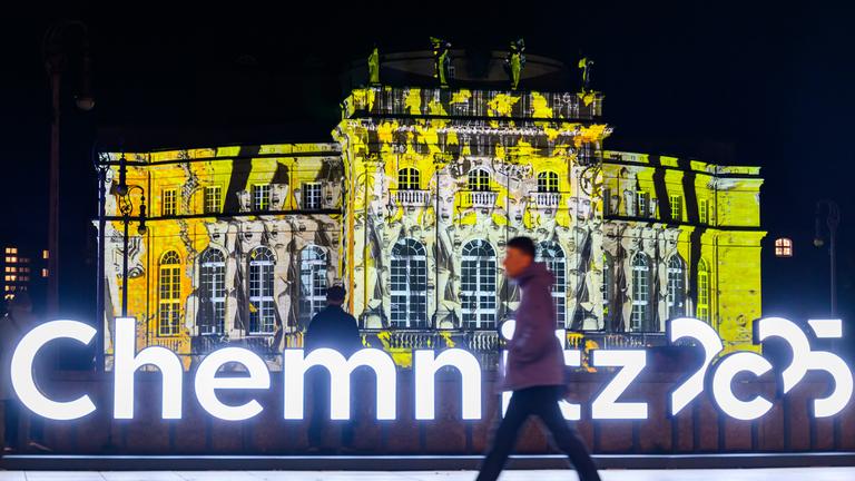 Lichtinstallation des polnischen Künstlers Ari Dykier. Es sieht aus wie ein gelbes Schloss. Außerdem steht in leuchtender Schrift "Chemnitz 2025".