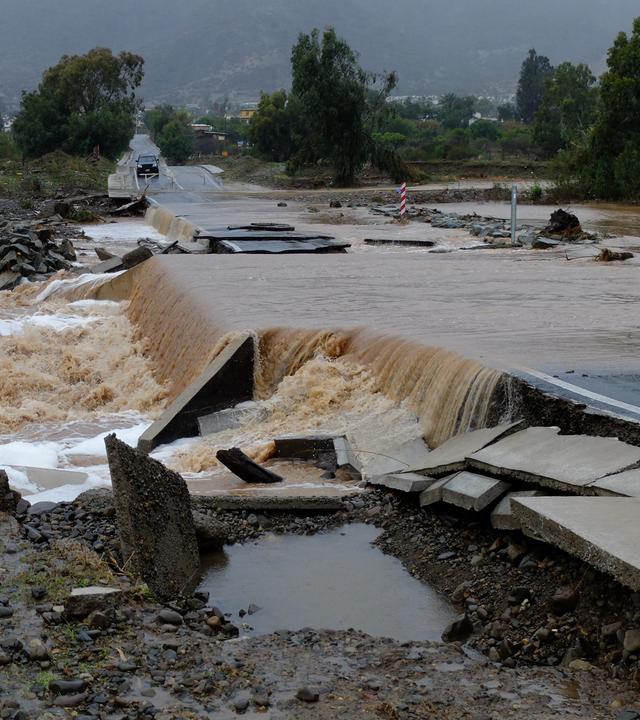 Chile, La Ligua: Wassermassen fließen über eine Landstraße, die La Ligua mit Valle Hermoso verbindet, nachdem der Fluss La Ligua aufgrund heftiger Regenfälle über die Ufer getreten ist.