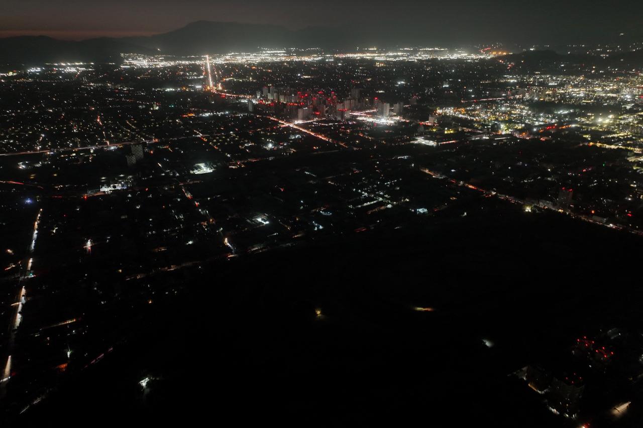 Straßen und Gebäude in Chile sind von Weitem im dunklen zu sehen. Nur teilweise leuchtet Licht.