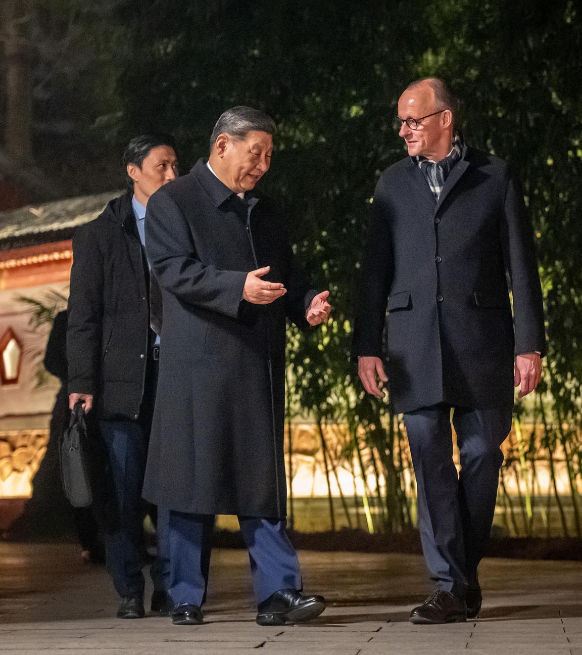 Bundeskanzler Friedrich Merz (CDU,r) geht neben Xi Jinping, Präsident von China, am Staatsgästehaus und begleitet von Dolmetschern zu einem Abendessen. 