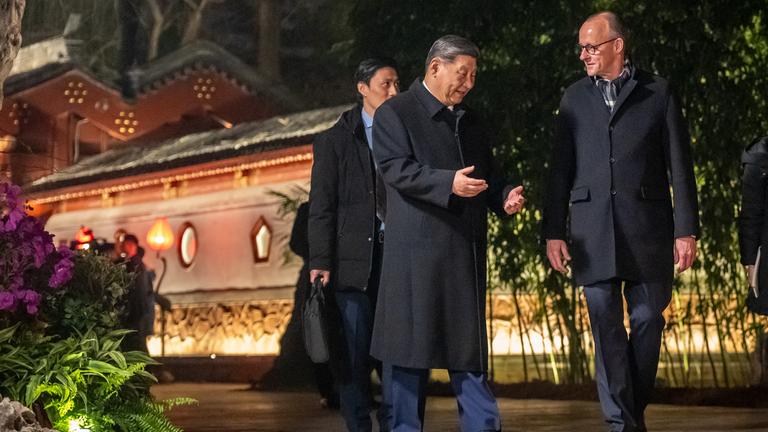 Bundeskanzler Friedrich Merz (CDU,r) geht neben Xi Jinping, Präsident von China, am Staatsgästehaus und begleitet von Dolmetschern zu einem Abendessen. 