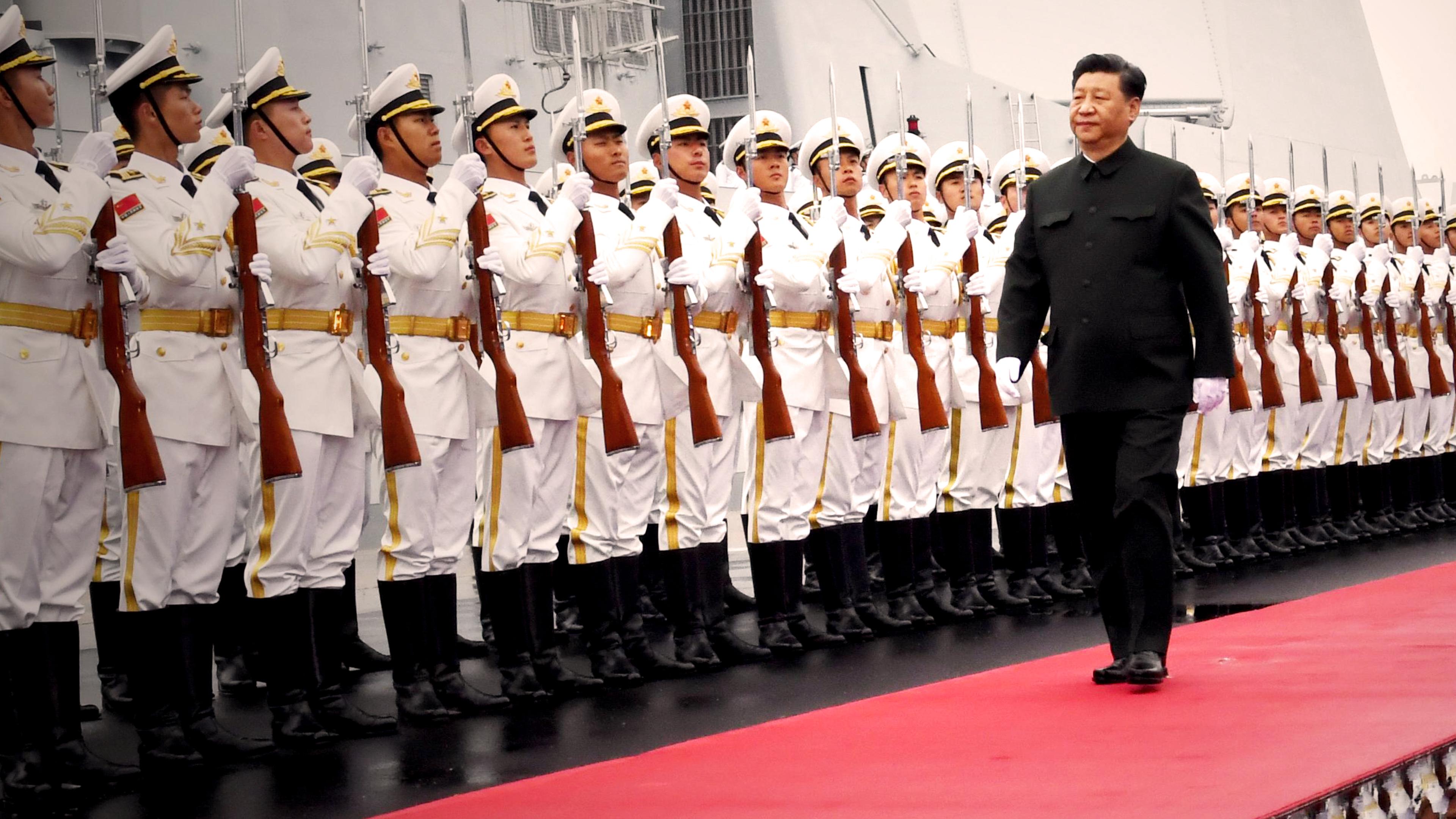 Xi Jinping läuft eine Soldatenreihe auf einem roten Teppich ab.