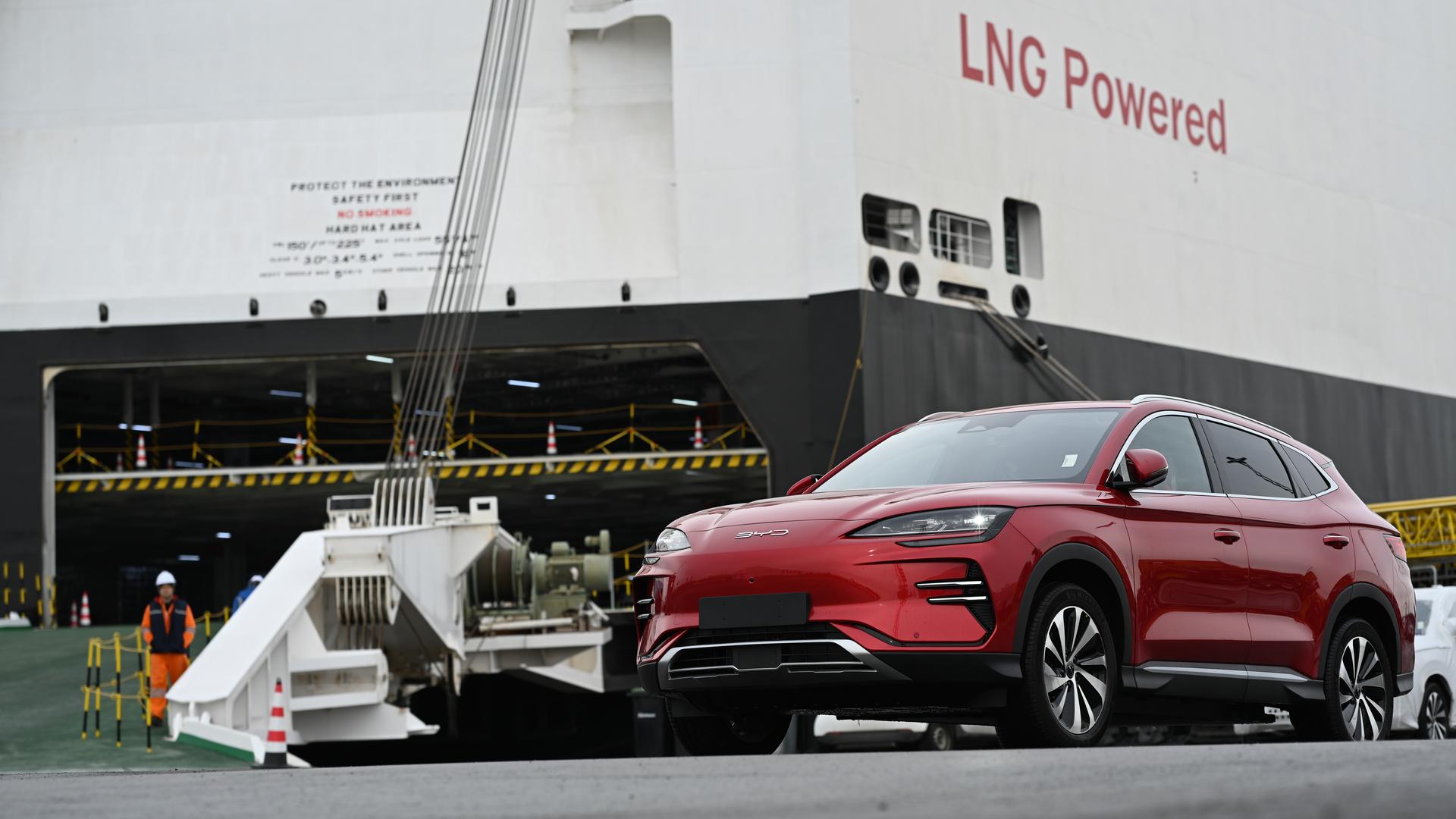 Ein Neuwagen des Modells ·Seal· des chinesischen Autoherstellers BYD steht vor dem Autofrachter BYD Explorer No.1" auf dem der Schriftzug "LNG Powered" zu lesen ist