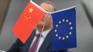 Fahnen Chinas und der EU vor Außenminister Boris Pistorius, unscharf im Hintergrund