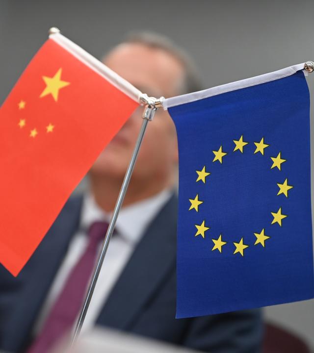 Fahnen Chinas und der EU vor Außenminister Boris Pistorius, unscharf im Hintergrund