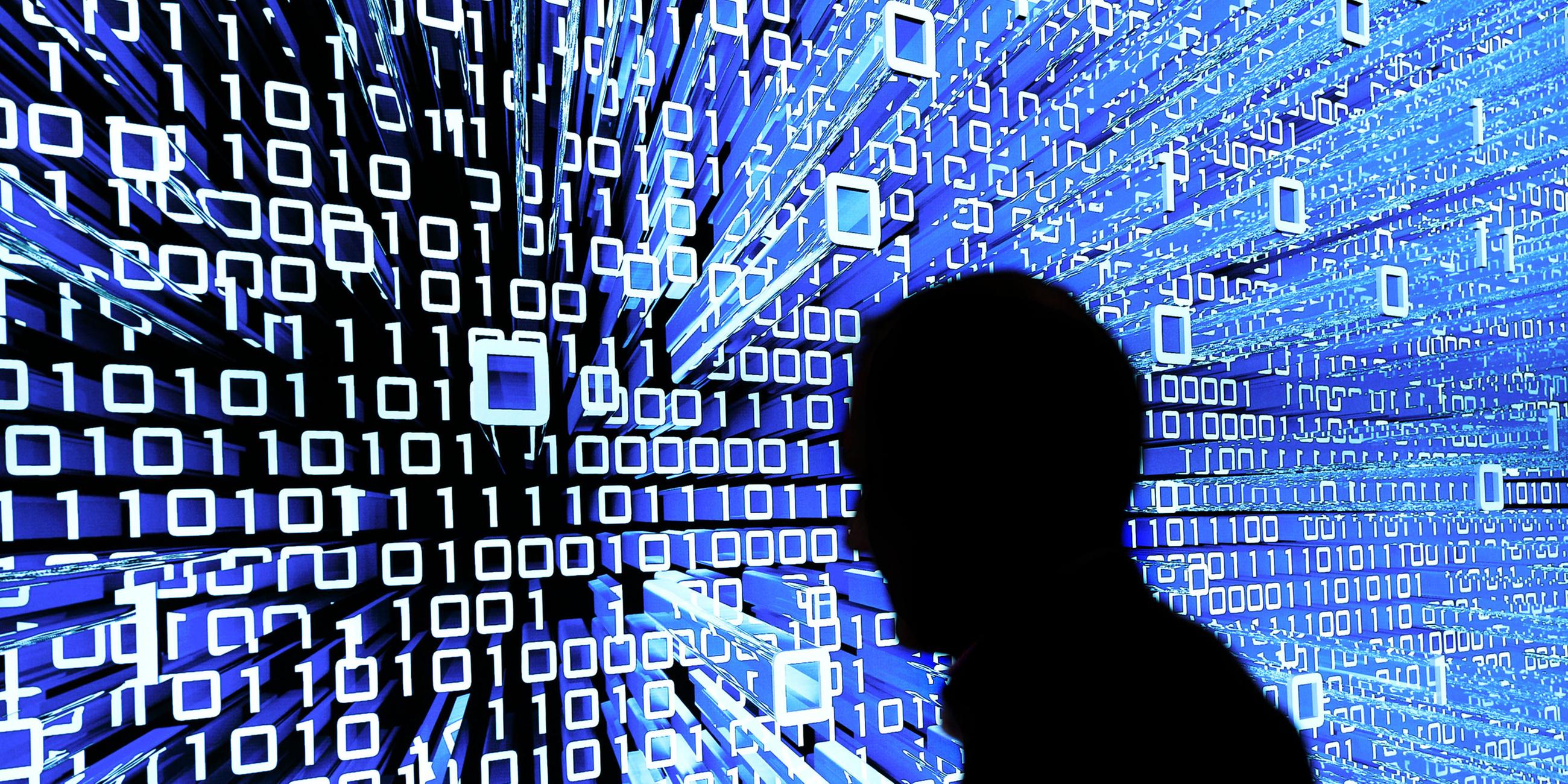 Schatten einer Person vor einem Leuchtdisplay mit Programmiercode. 