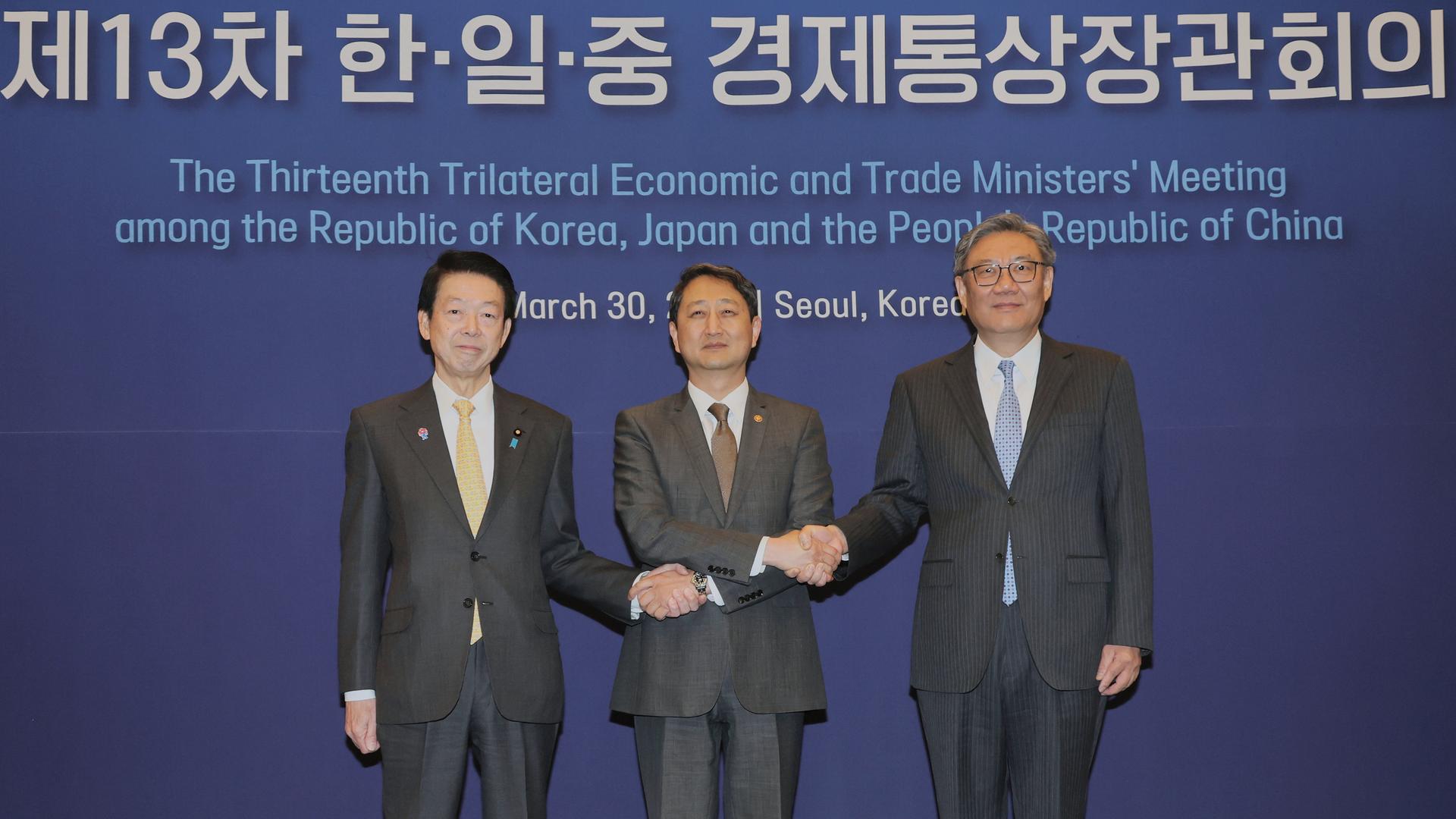 Gelbe Krawatte, braune Krawatte, blaue Krawatte. Drei Männer in dunklen Anzügen. Der in der Mitte überkreuzt die Arme für einen simultanen Handshake mit seinen beiden Nachbarn. Das Foto dieses politischen Treffens sieht unspektakulär aus, doch ist es nicht.