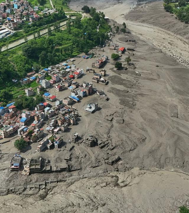 Nach Sturzfluten im nepalesischen Distrikt Nuwakot stehen beschädigte Häuser gefährlich nahe an den angeschwollenen, mit Treibgut verstopften Ufern des Trishuli-Flusses. 