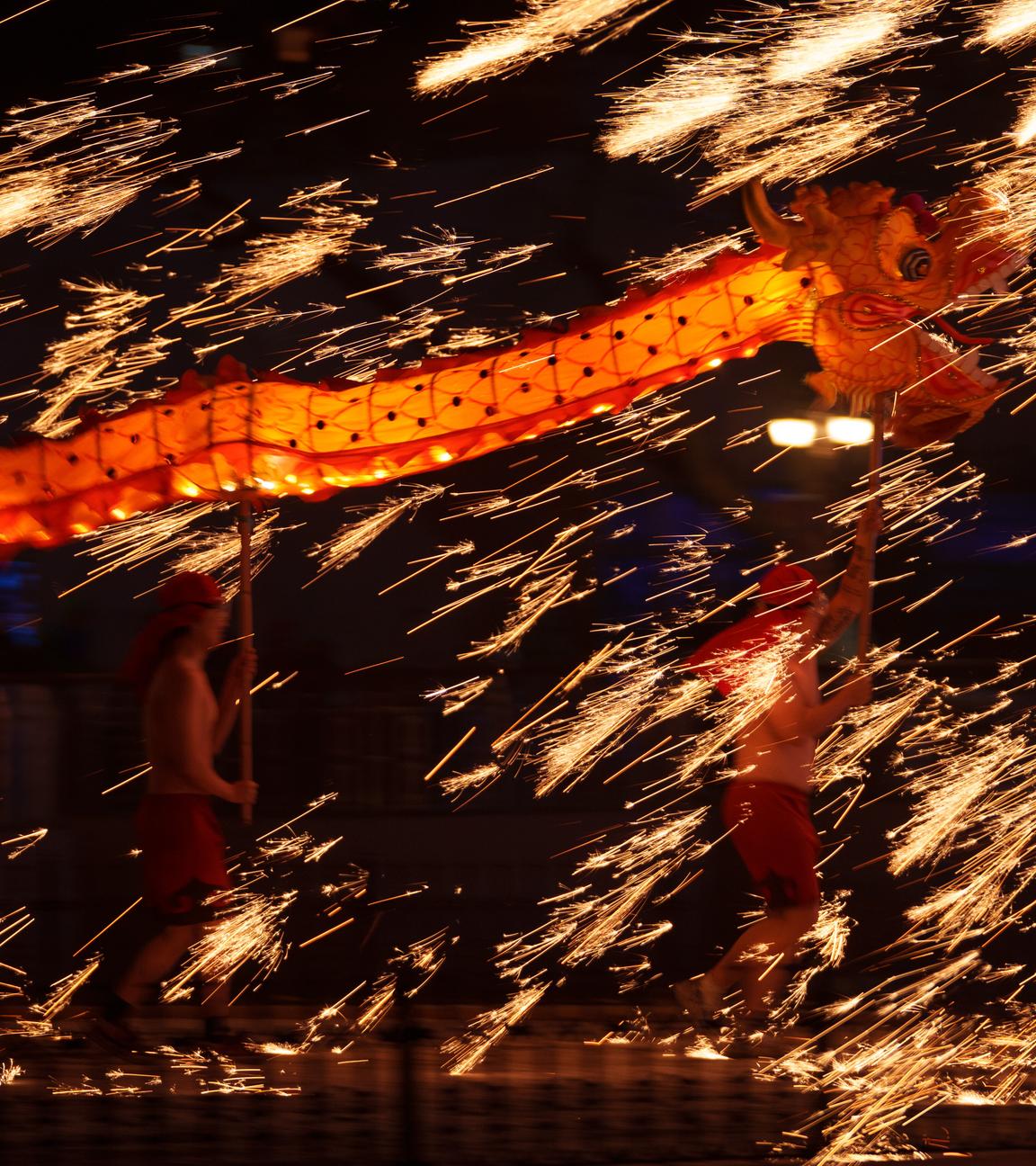 Feuerkünstler tragen einen Drachen während einer Feuerwerksvorführung. 