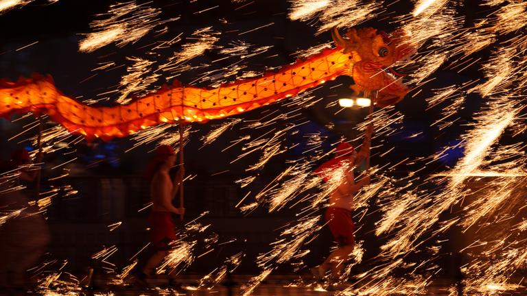 Feuerkünstler tragen einen Drachen während einer Feuerwerksvorführung. 