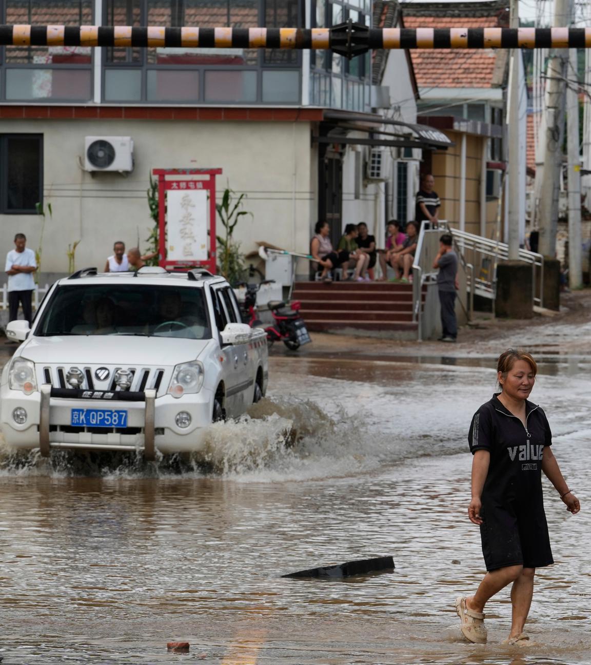 Eine Frau geht durch eine überflutete Straße nach starkem Regen im Bezirk Miyun am Stadtrand von Peking, China.