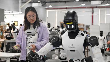 Mitarbeiter trainiert einen Roboter an einer Produktionslinie in Shanghai, China.