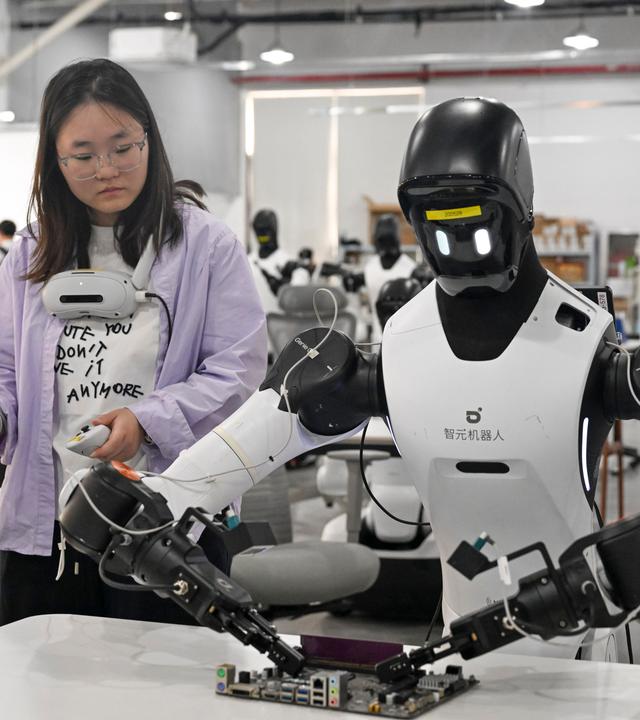 Mitarbeiter trainiert einen Roboter an einer Produktionslinie in Shanghai, China.