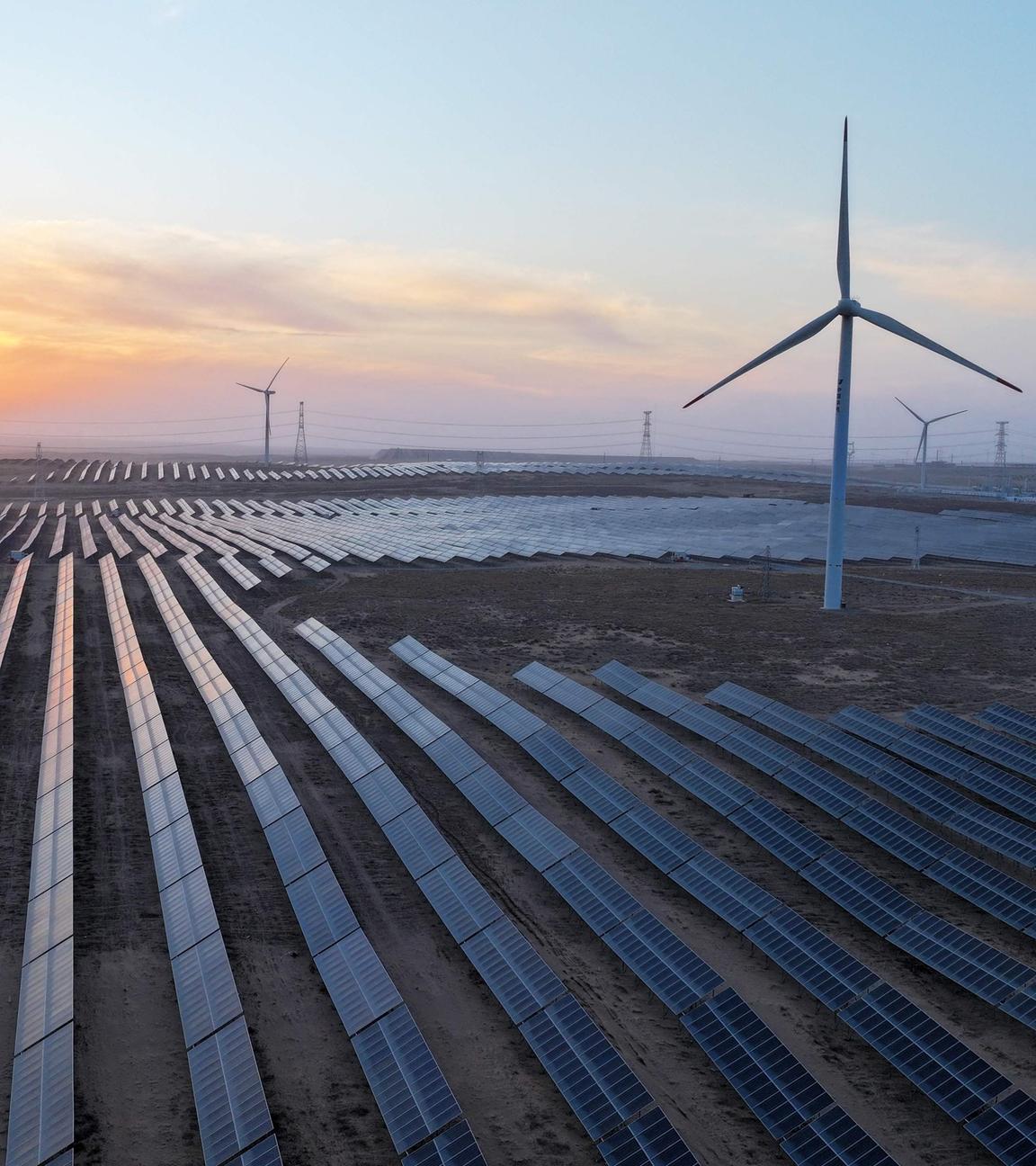 ELuftaufnahme einer Ebene mit Solaranlagen und Windrädern.