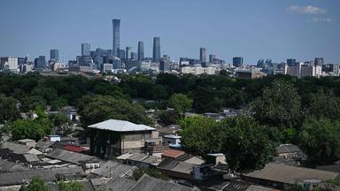 Chinesische Stadt mit Hochhäusern im Hintergrund, Slums im Vordergrund. 