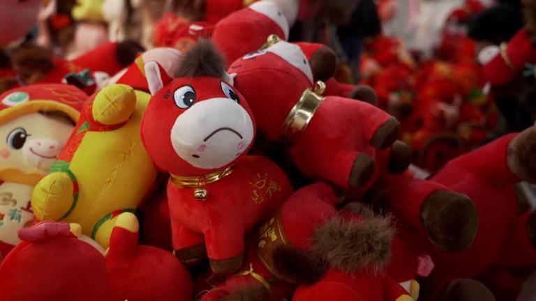 Viele Stofftiere, die meisten rot. Im Zentrum des Bildes ein traurig schauendes rotes Stoffpferd.