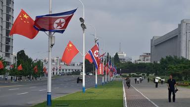 Chinesische und Nordkoreanische Flaggen in einer Straße in Pyongyang.
