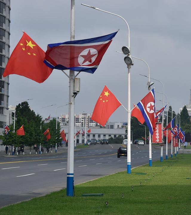Chinesische und Nordkoreanische Flaggen in einer Straße in Pyongyang.