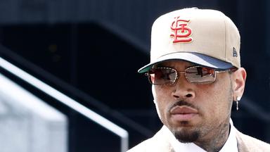 Auf dem Bild ist zu sehen: Nahaufnahme von Chris Brown. Er trägt eine cremefarbene Baseballkappe und eine Sonnenbrille.