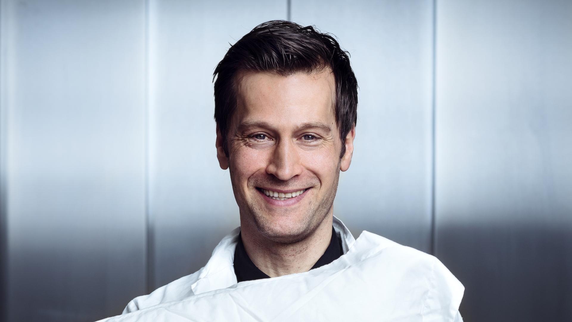 Der Autor und Wissenschaftler Christian Benedict hält ein weißes Kissen.