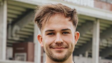 Das Bild zeigt St. Paulis Nachwuchstrainer Christian Dobrick. Er trägt ein schwarzes Fußballtrikot und lächelt in die Kamera.