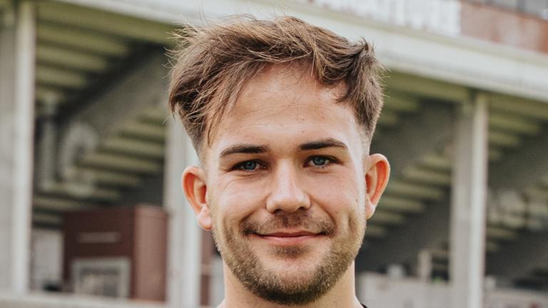 Das Bild zeigt St. Paulis Nachwuchstrainer Christian Dobrick. Er trägt ein schwarzes Fußballtrikot und lächelt in die Kamera.