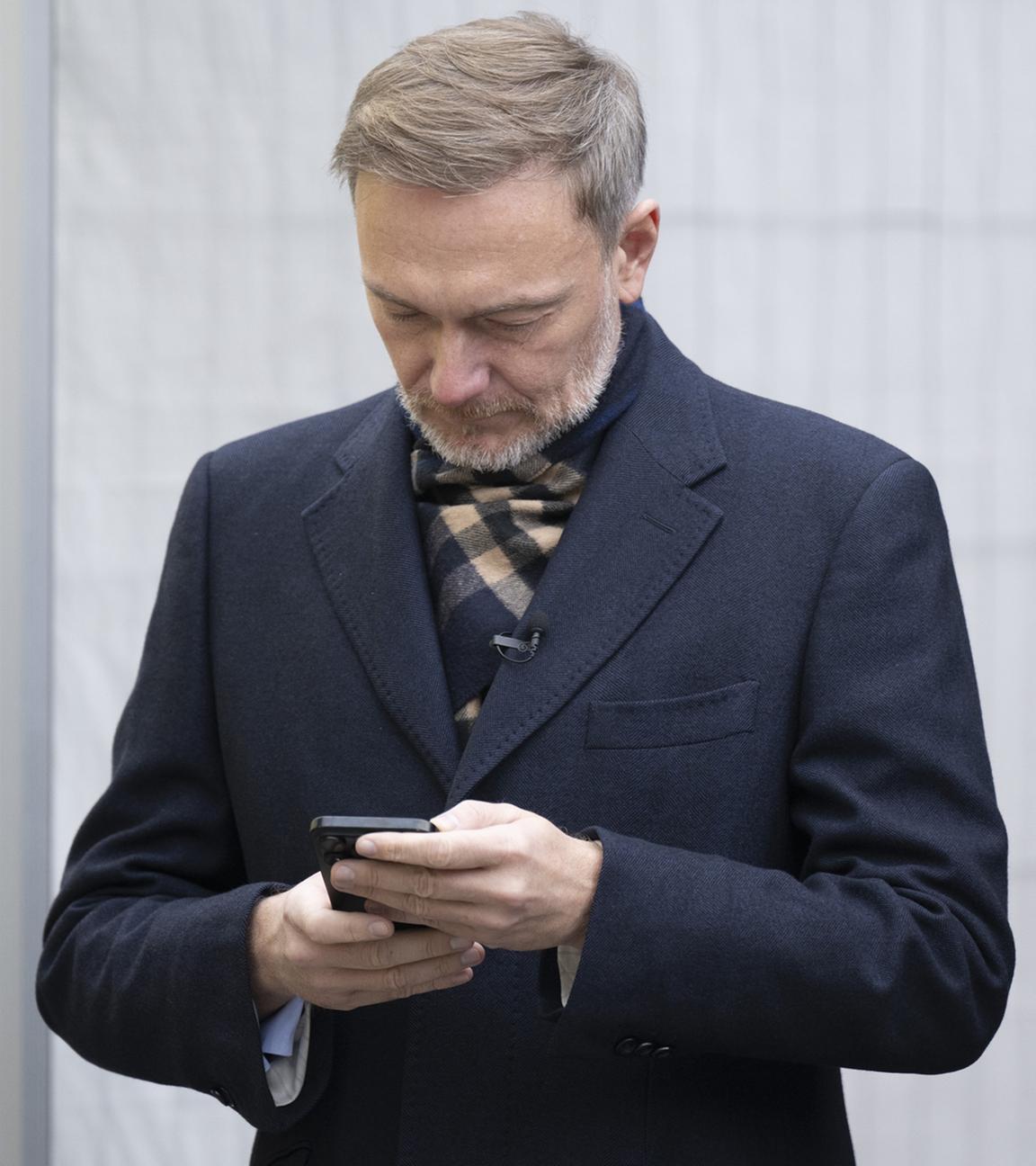 Christian Lindner schaut auf ein Smartphone
