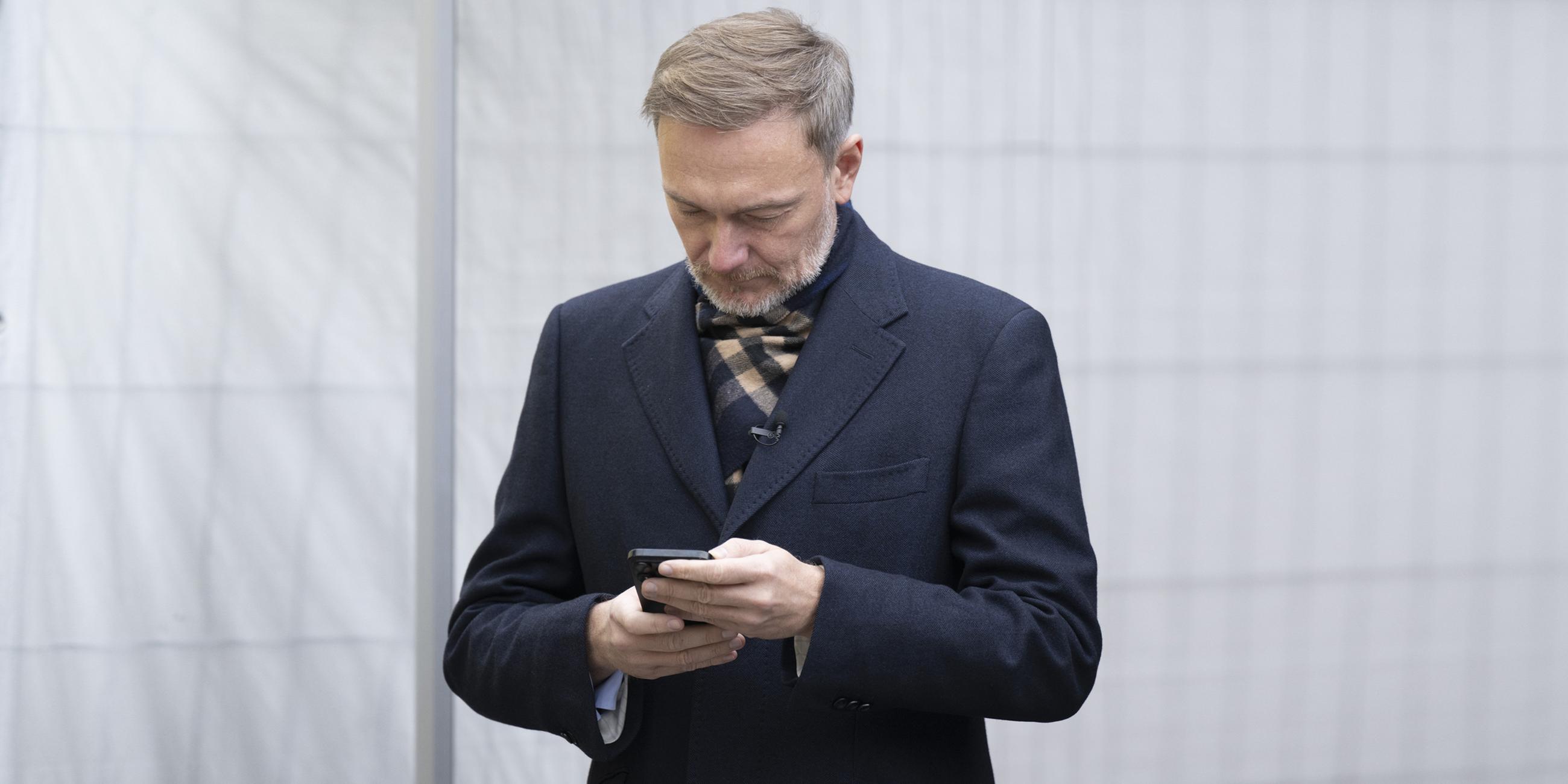 Christian Lindner schaut auf ein Smartphone