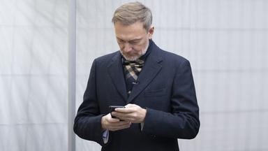 Christian Lindner schaut auf ein Smartphone