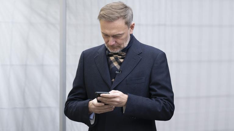 Christian Lindner schaut auf ein Smartphone