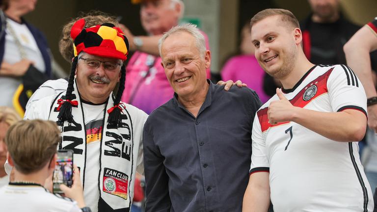 Fußball-EM 2024, Schweiz - Deutschland: Christian Streich, Ex-Trainer des SC Freiburg, lässt sich mit Fans auf der Tribüne fotografieren.