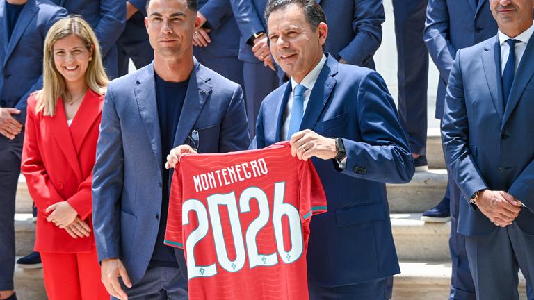 Portugals Premierminister Luis Montenegro hält ein Trikot mit seinem Namen in die Höhe, links neben ihm steht Christiano Ronaldo